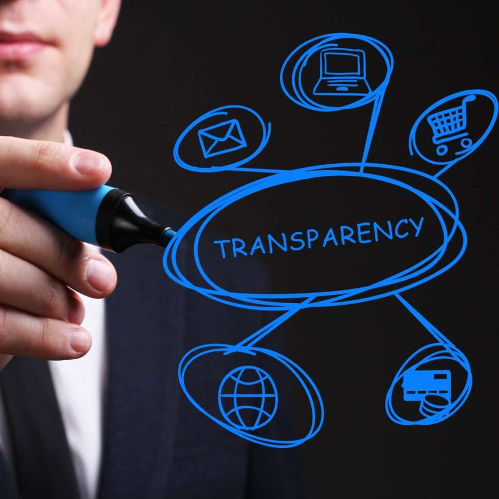 A white man in a business casual outfit stands in front of a transparent glass board.