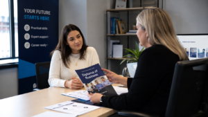 Adult student reviewing Diploma of Business course information with an education advisor in a modern office while discussing career development and study pathways.