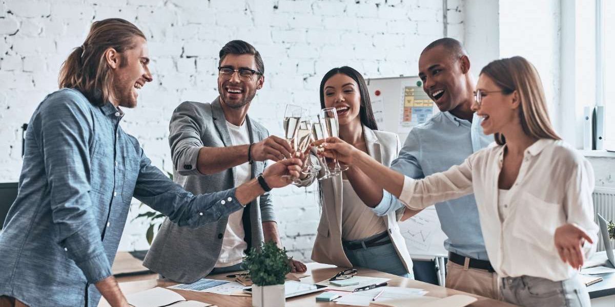 A group of diverse young professionals, standing in a modern board room, raise their glasses in a toast, celebrating a success.